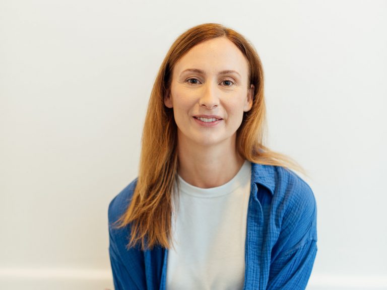 Diana Bluhm lehnt vor einer Wand und guckt in die Kamera