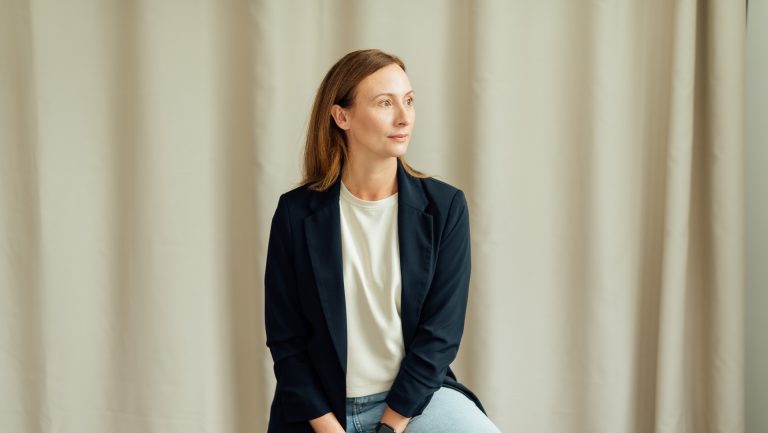 Diana Bluhm schaut nach links und sitzt auf einem Hocker