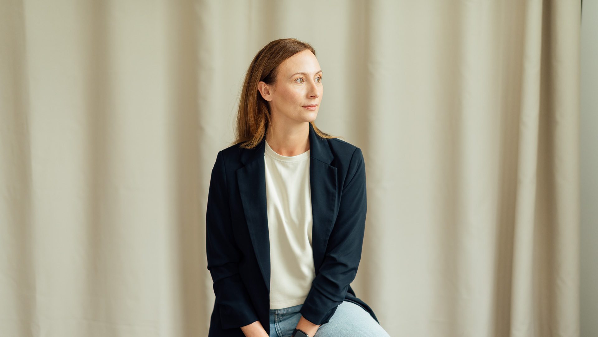 Diana Bluhm schaut nach links und sitzt auf einem Hocker